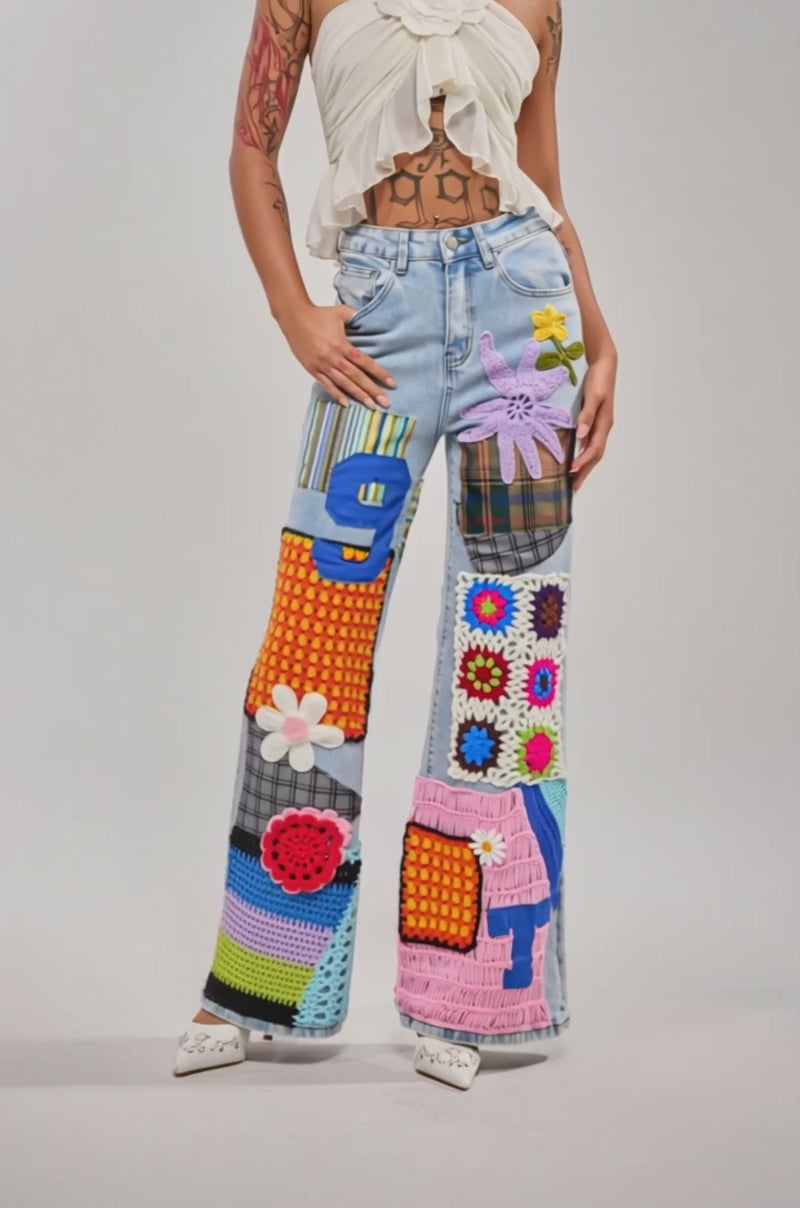 A video of a model wearing the CUTE LIKE ME RELAXED DENIM wide-leg jeans in light blue, featuring crochet patchwork with flowers, numbers, and textured fabrics, paired with white heeled shoes for a playful street style vibe. 