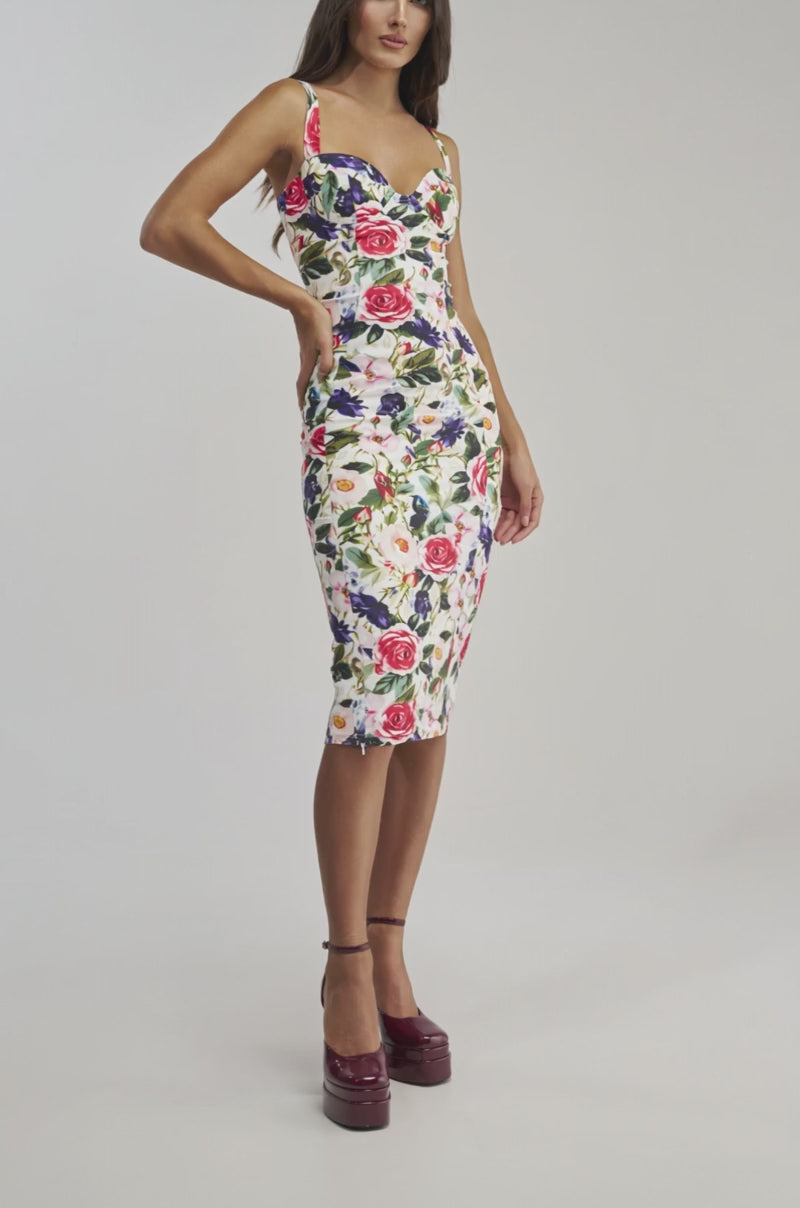 Video of a woman modeling the TALK IS CHEAP FLORAL MIDI DRESS, featuring a colorful pattern of pink and red roses with green leaves on a light background.