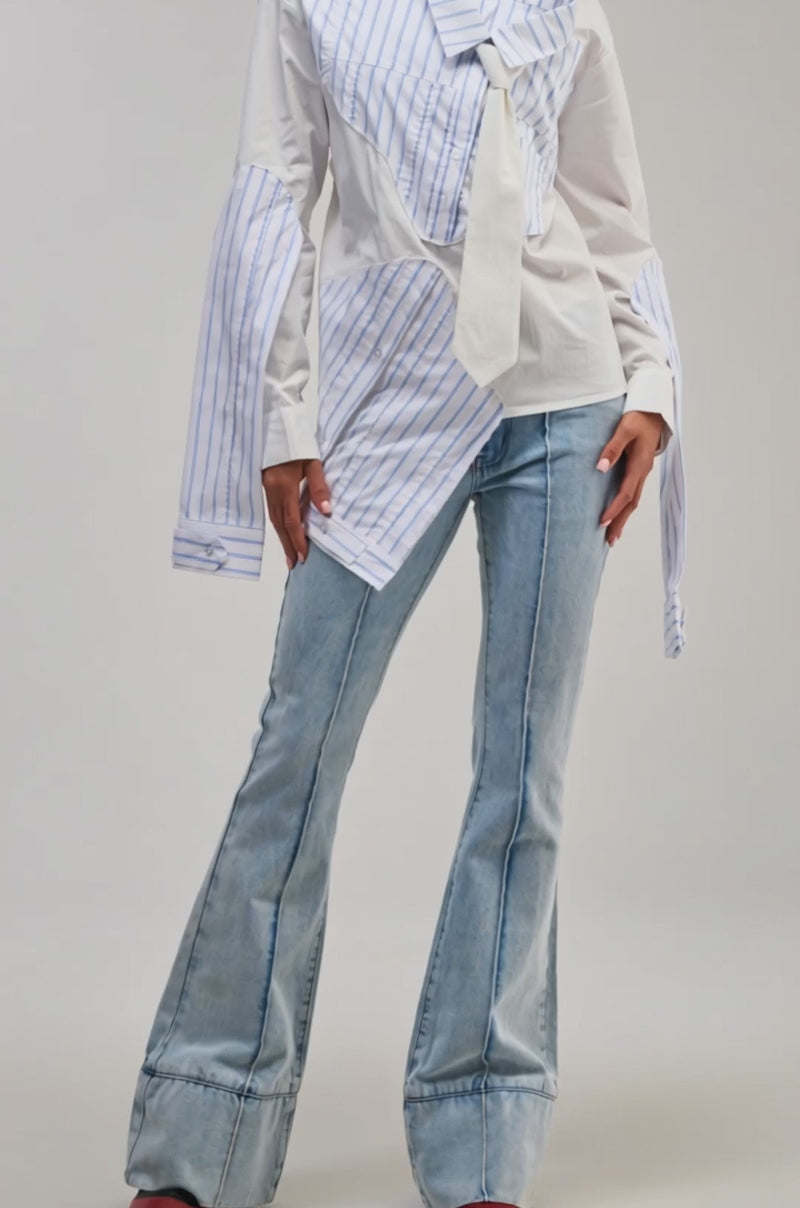 Video of a woman modeling the HOT MESS POPLIN BLOUSE—a deconstructed white button-up with blue stripes and extra sleeves.