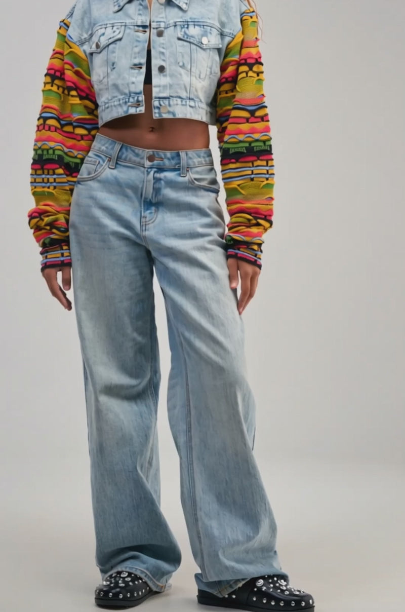 Video of a woman modeling the THROWBACK KNIT SLEEVE DENIM JACKET—featuring a retro-chic cropped fit with colorful knit sleeves.
