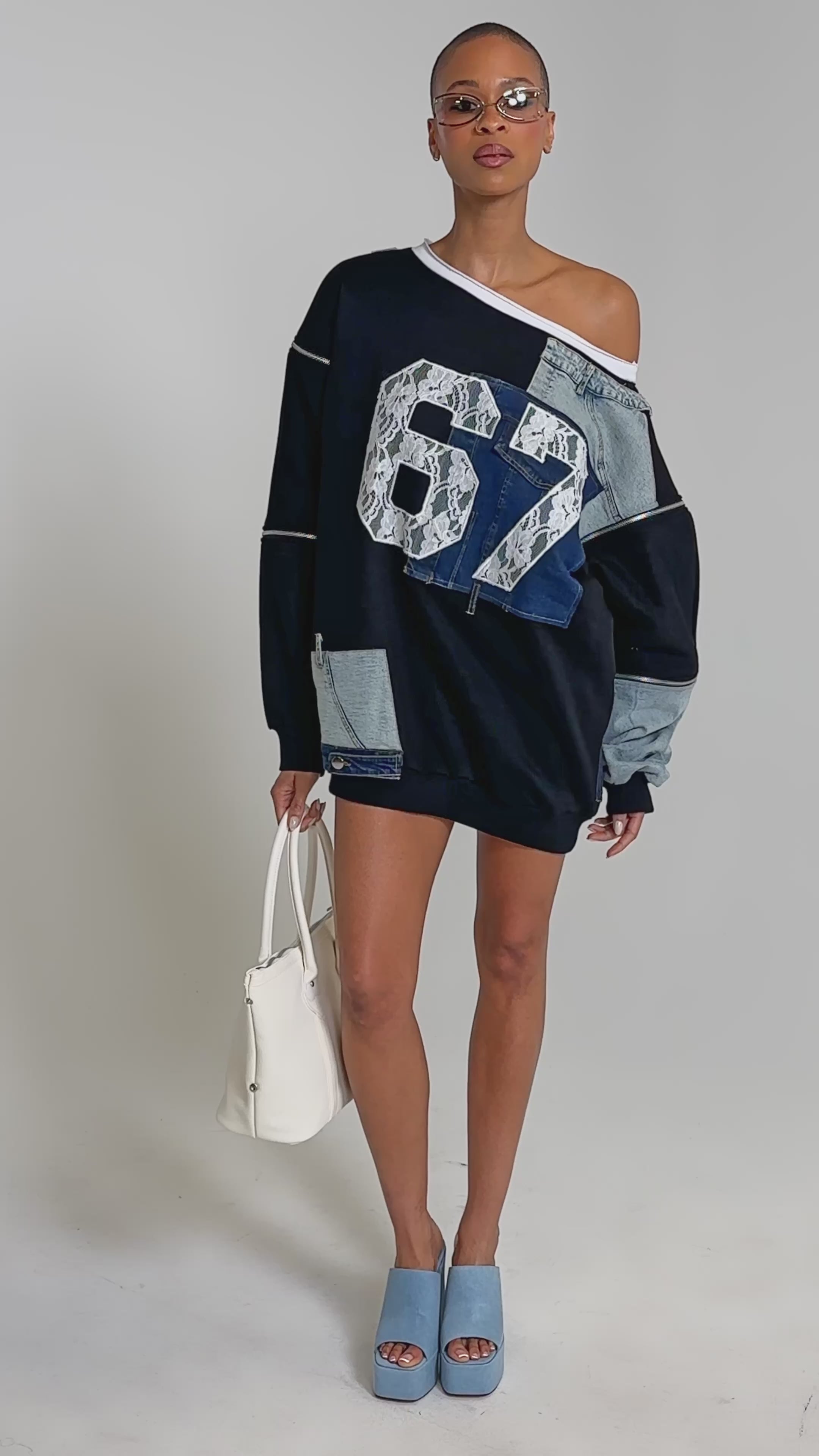 Video of woman modeling the DREAM TEAM FRENCH TERRY MINI DRESS with patchwork denim, lace accents, and a bold "67" on the front, sporting short hair, sunglasses, and carrying a white bag.