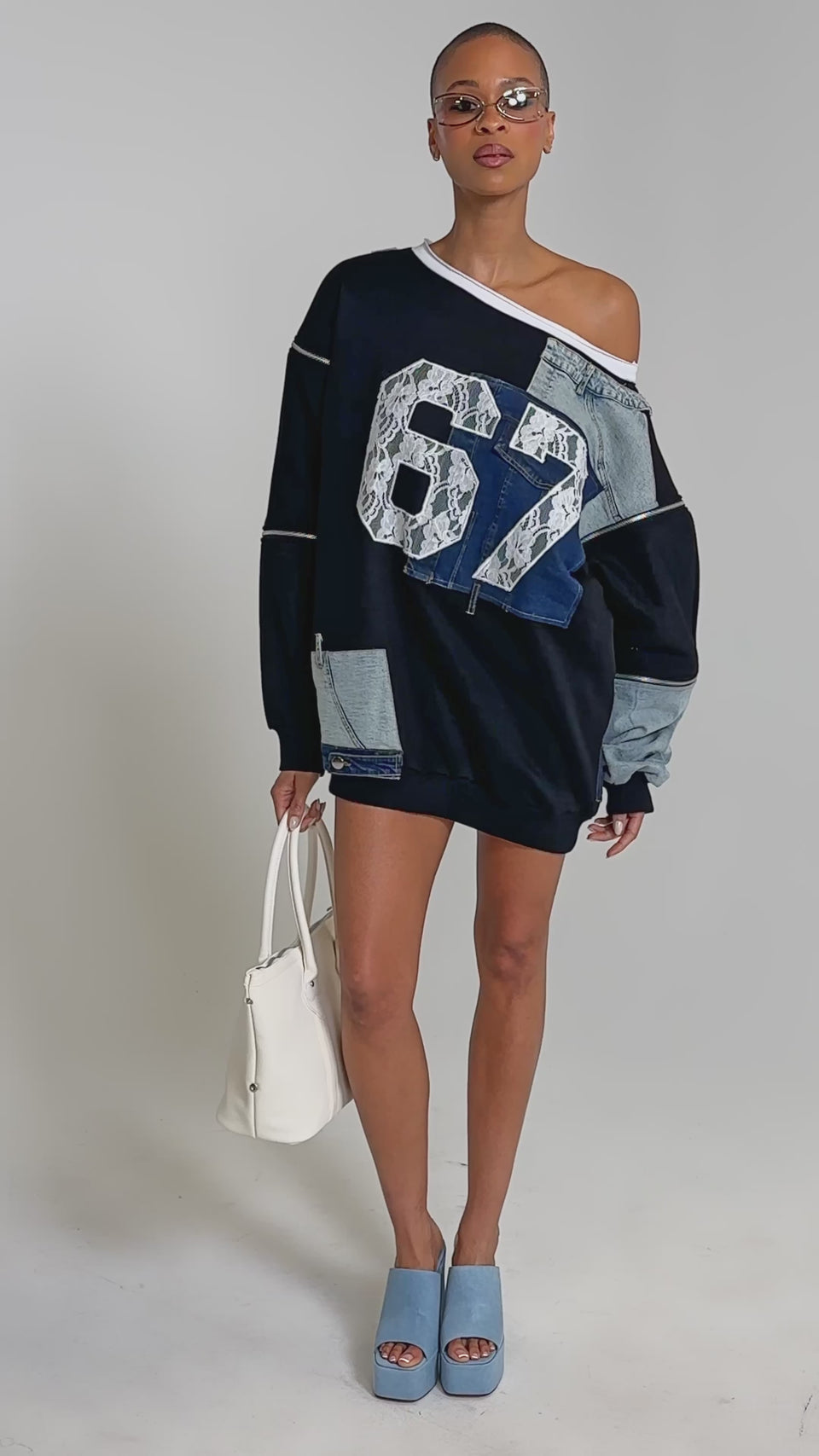 Video of woman modeling the DREAM TEAM FRENCH TERRY MINI DRESS with patchwork denim, lace accents, and a bold "67" on the front, sporting short hair, sunglasses, and carrying a white bag.