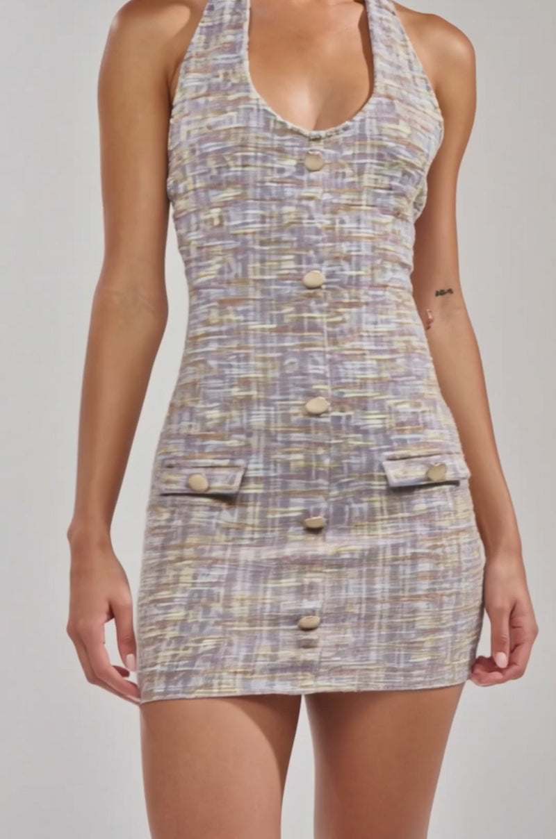 A video of a woman in the LOWKEY FIRE TWEED MINI DRESS IN LILAC, a halter-neck mini dress with front buttons and two small pockets. 