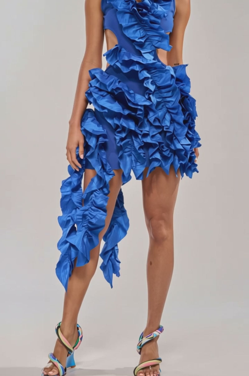 A video of a woman wearing the CRAZIER THAN YOUR EX FLOCKED MINI DRESS IN BLUE, featuring vibrant ruffles and layered details. 