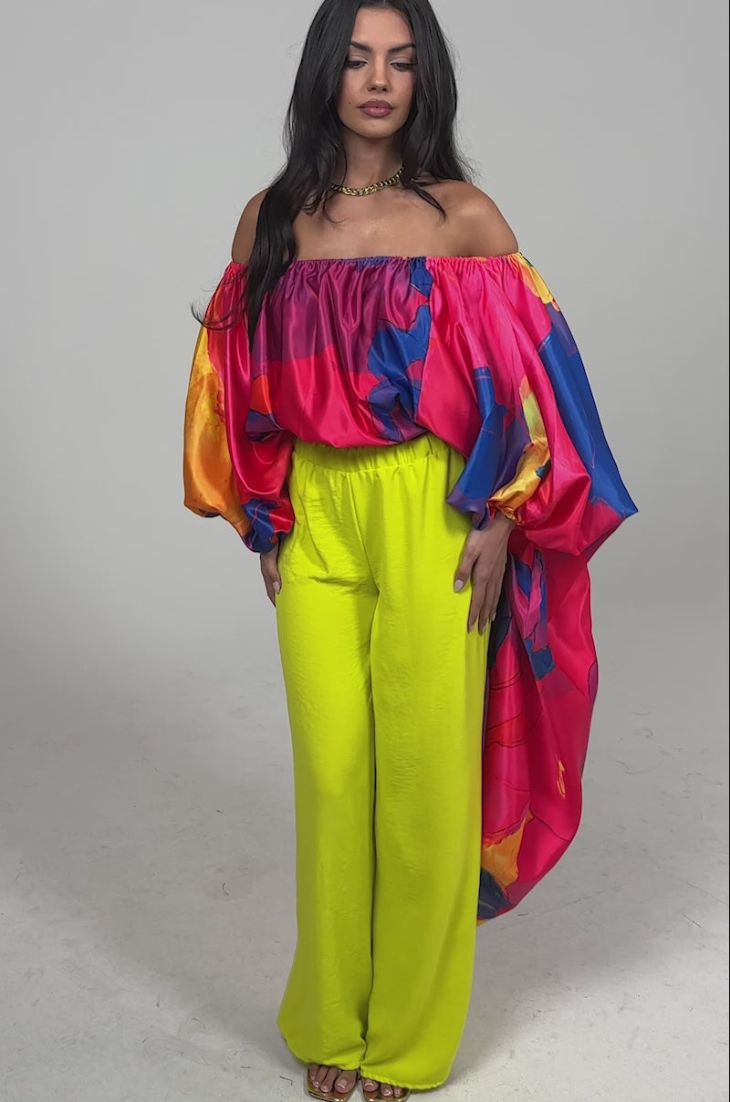 Video of woman modeling the BRIGHTEST IN THE CITY PALAZZO PANT, styled with beige open-toe heels and a colorful flowy top featuring pink, blue, and orange patterns