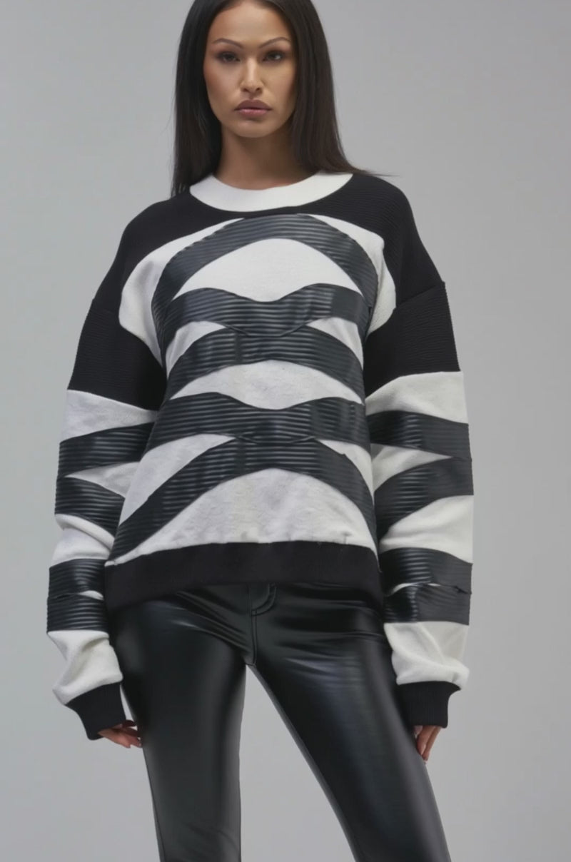 Video of a woman modeling the CROSSING LINES SWEATSHIRT, featuring a black-and-white 3D wave-textured abstract pattern.