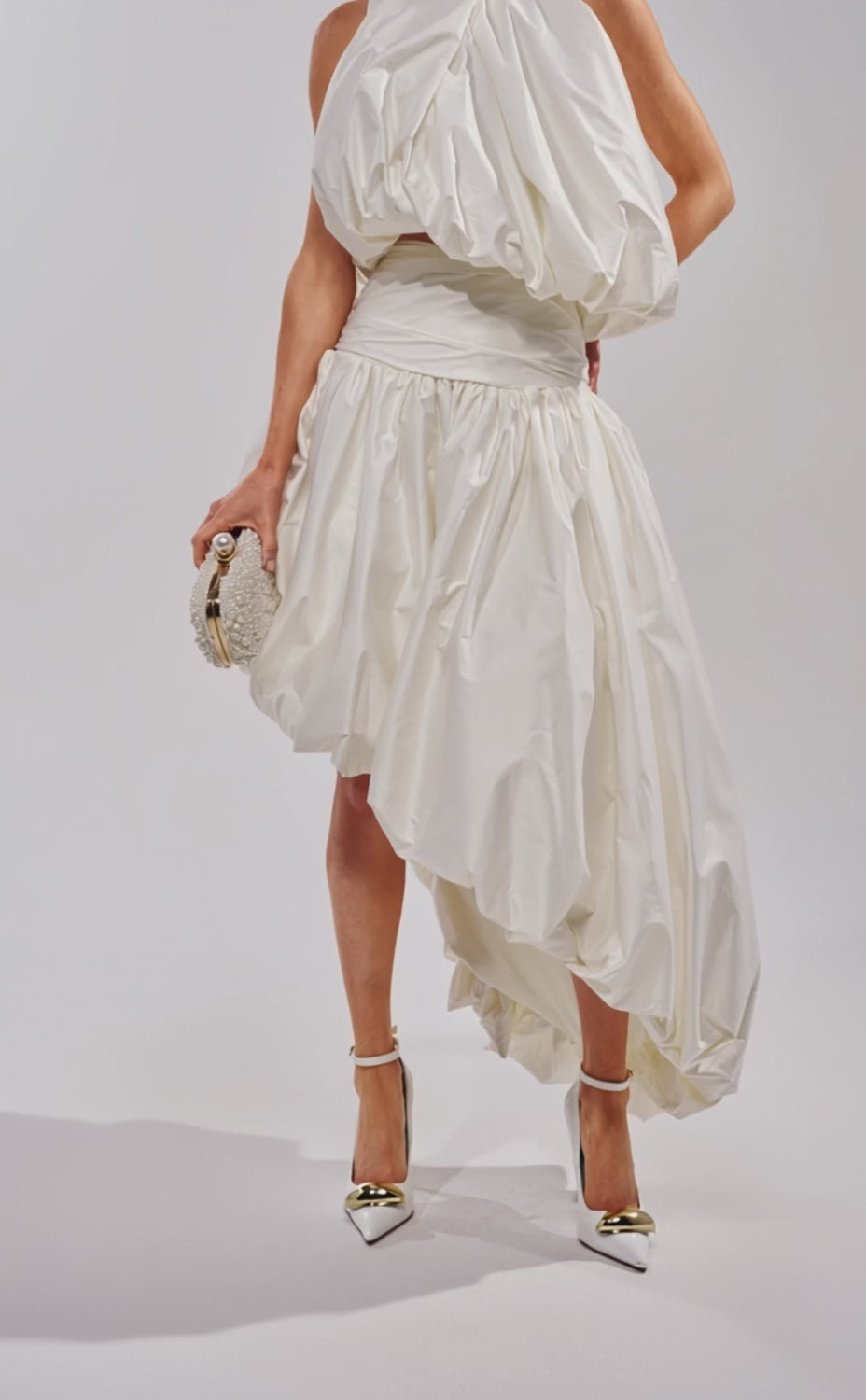 A video of a woman wearing the HEAD IN THE CLOUDS HIGH LOW SKIRT with an asymmetrical hemline and ruched waist. 
