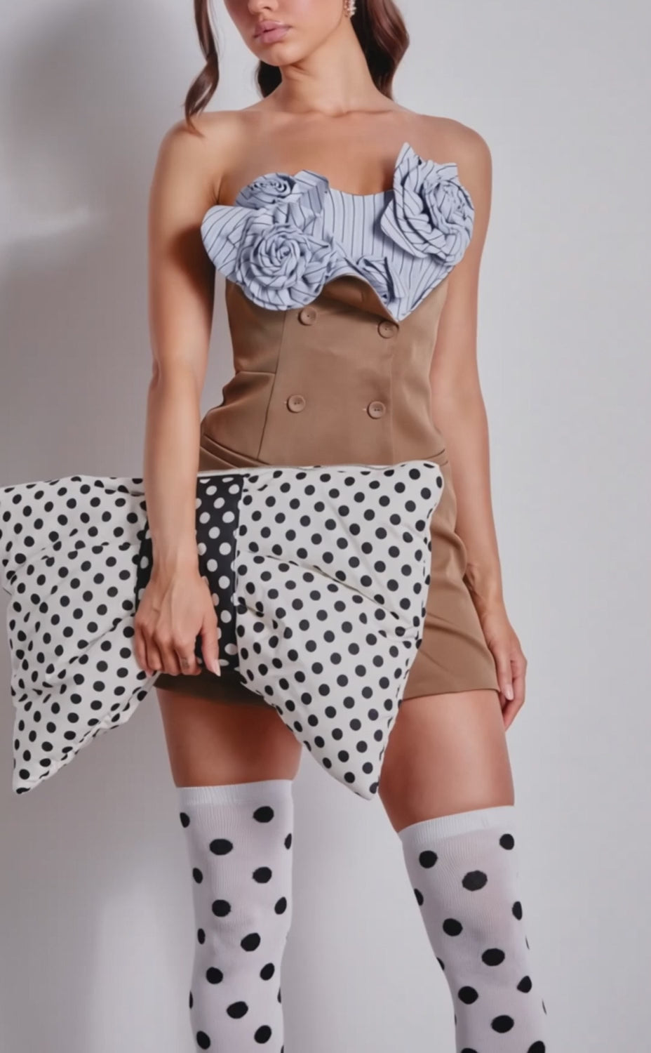 A video of a woman in a brown mini dress and black platform heels, holding a polka dot purse. She is wearing the playful CALL ME DOTTIE KNEE HIGH SOCKS with bold polka dot design.