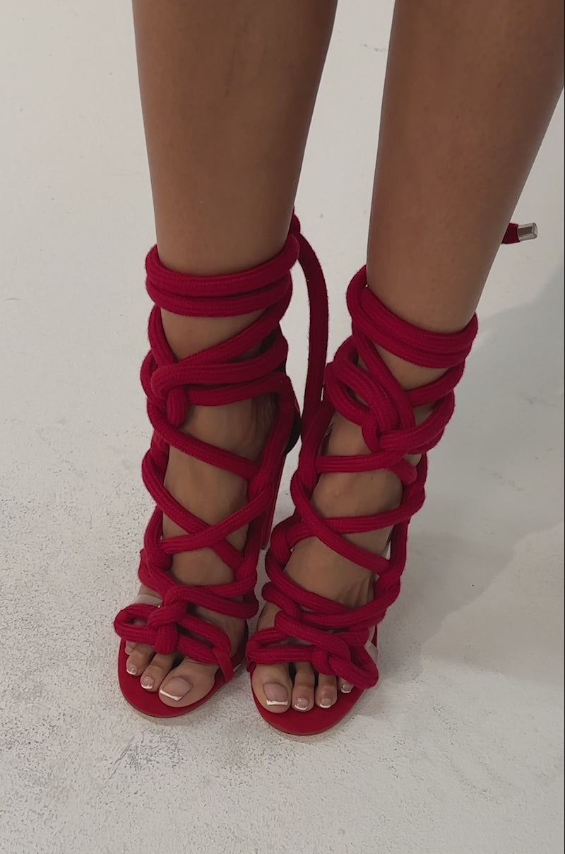 Video of woman modeling the AKIRA GOLD RED ROPE STRAP SANDAL with thick braided straps wrapped around her lower legs, styled with denim.