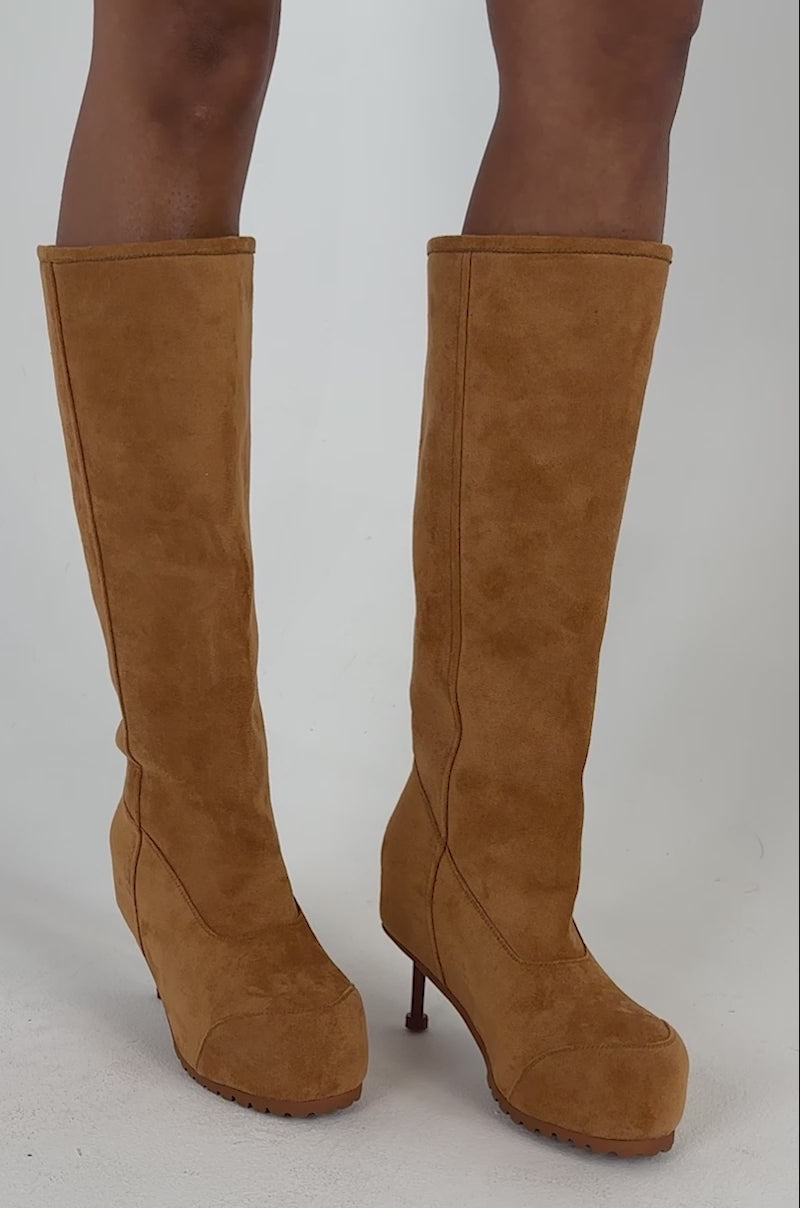 Video of a woman modeling the AZALEA WANG CLEDQYN CHESTNUT SUEDE STILETTO BOOTIE sits on a white block, looking confidently at the camera.