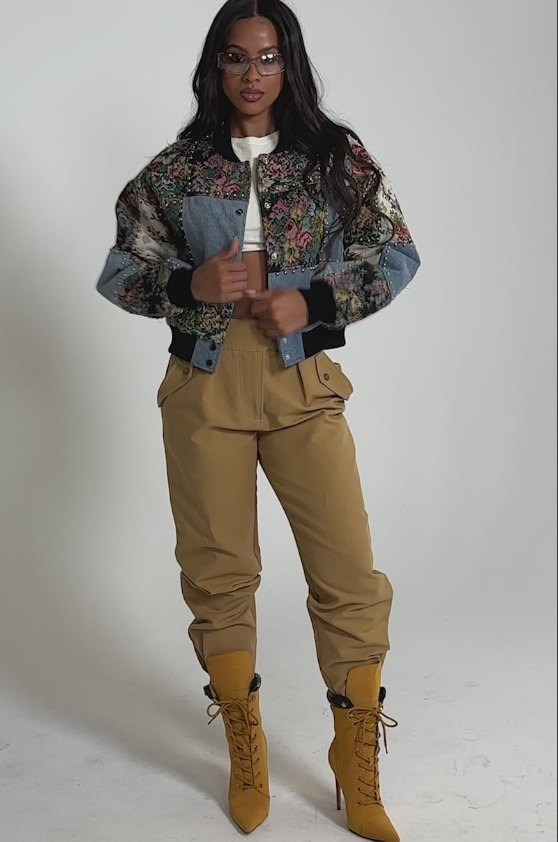 Video of woman modeling the SWEET TALKER PATCHWORK BOMBER over a white crop top with high-waisted tan pants.