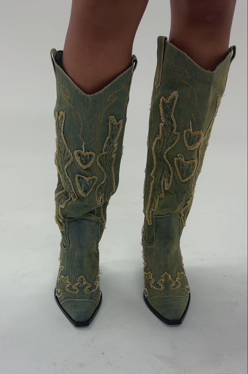 Video of woman modeling the AZALEA WANG HEINRICH DENIM WESTERN LOW HEEL BOOT with yellow embroidery stands on a light floor.