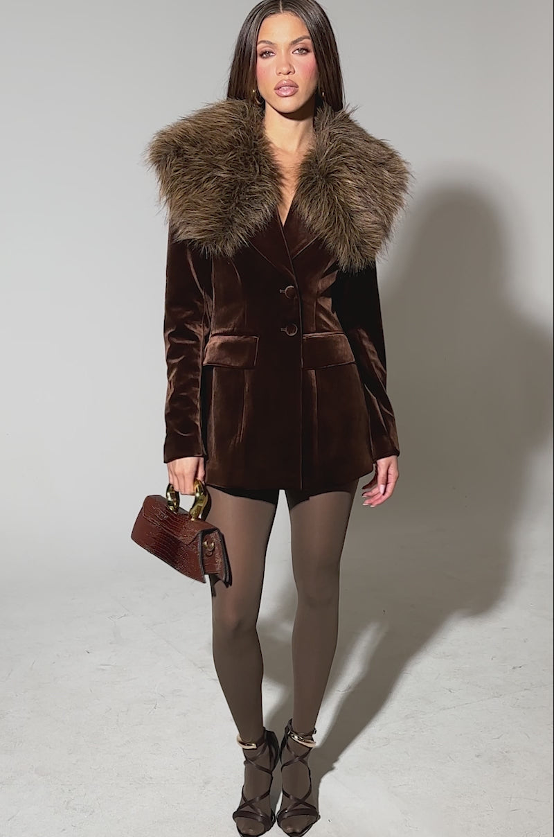 Video of woman modeling the SUNDAY VELVET BLAZER WITH REMOVABLE FUR COLLAR, paired with brown tights, black heels, and a small brown handbag