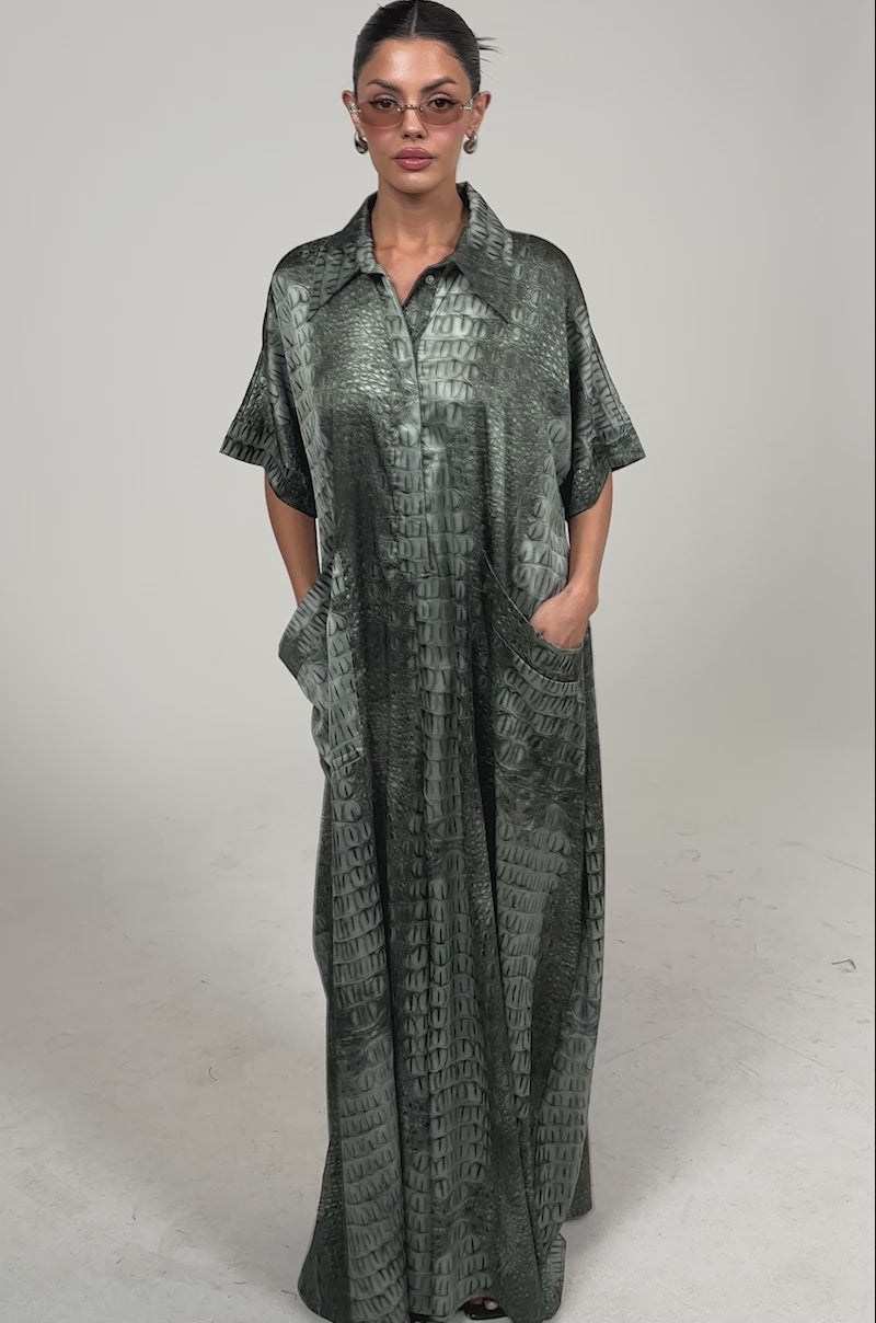 Video of woman modeling the SHE'S RICH OVERSIZED JUMPSUIT IN SNAKE, styled with a collar, short sleeves, and sunglasses.