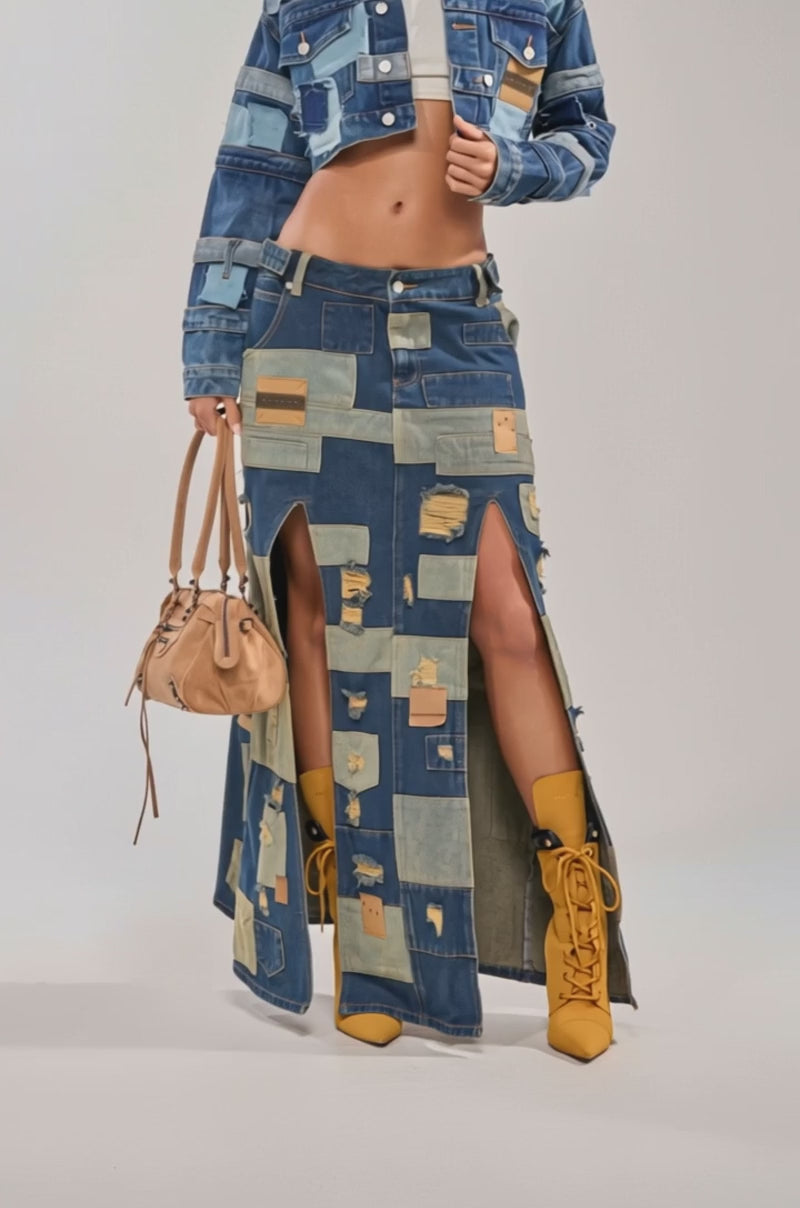 A video of a woman in festival styling—a PATCH ME UP DENIM MAXI SKIRT with front slits, cropped patchwork denim jacket, tan heeled boots, large sunglasses, and a small tan handbag.
