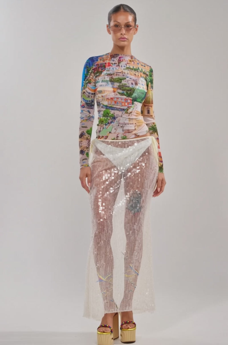 Video of woman modeling the AMALFI DAYS MESH TOP with a cityscape print, and a sheer white sequin skirt over white underwear, standing against a plain background.