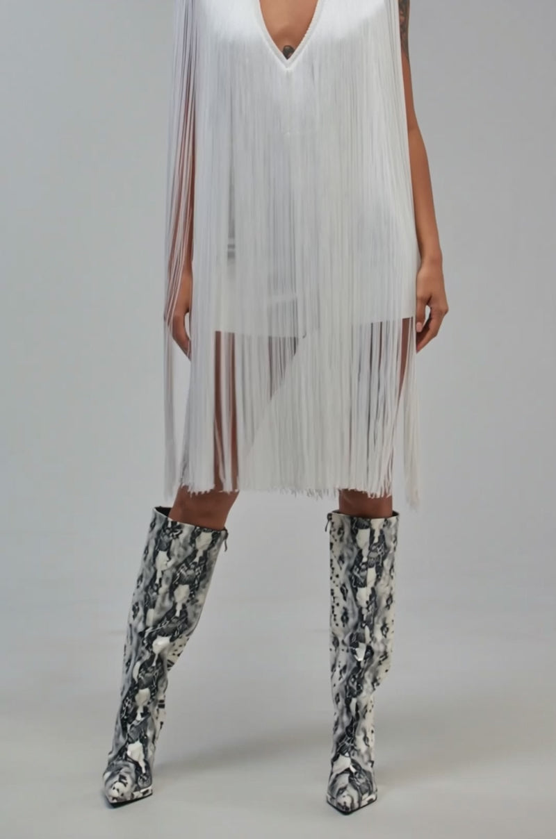 Video of a woman modeling the SHAKE IT FOR ME SLEEVELESS BANDAGE ROMPER WITH FRINGE IN WHITE.