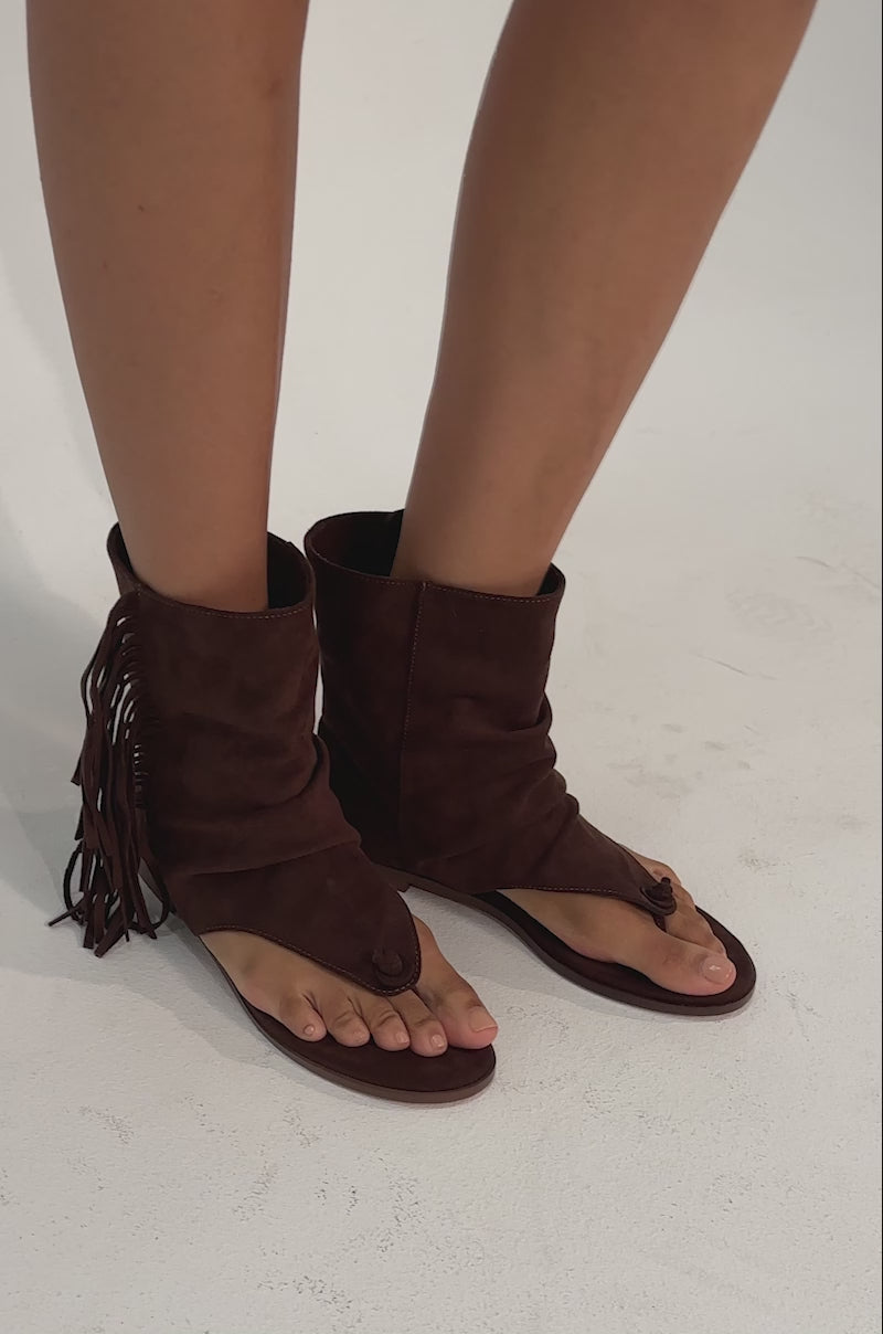 A video of a person wearing the AZALEA WANG FIDDA CHOCOLATE GLADIATOR FLAT SANDAL with slouchy, boho fringe details.