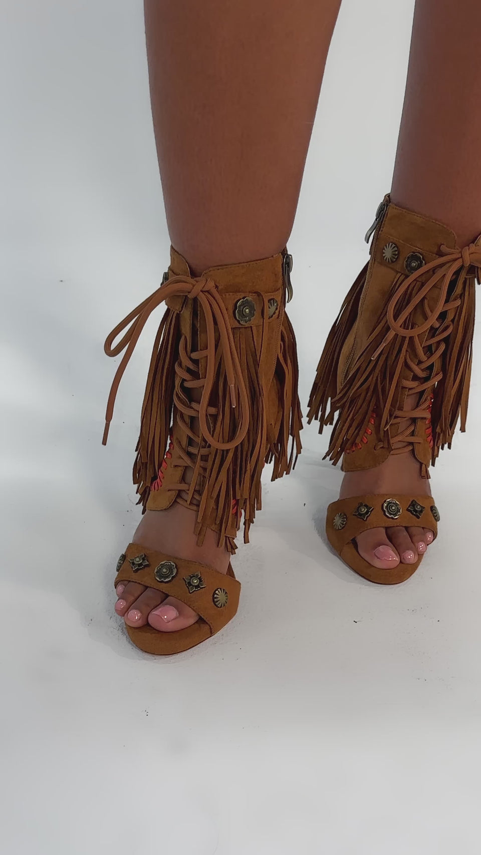 Video of woman modeling the AZALEA WANG SALGADO FRINGE GLADIATOR STILETTO SANDAL—tan faux suede with fringe, decorative stitching, metal studs, open toes and ankle straps