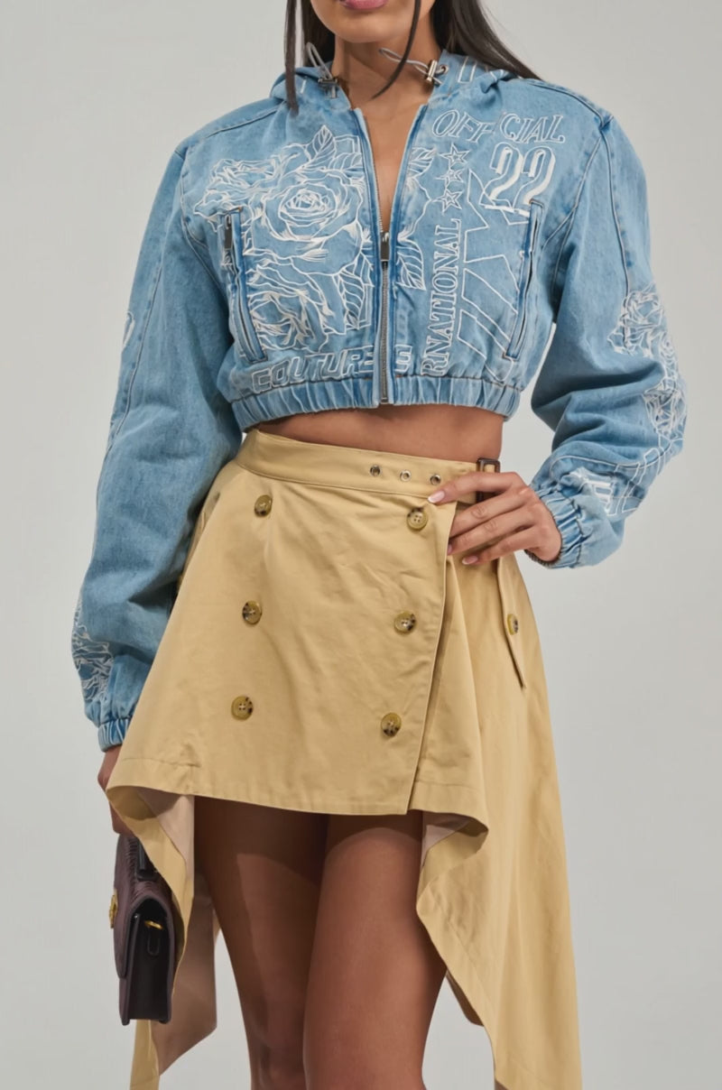 Video of a woman modeling the I SPY DENIM BOMBER—a blue cropped denim jacket with eye-catching embroidery.