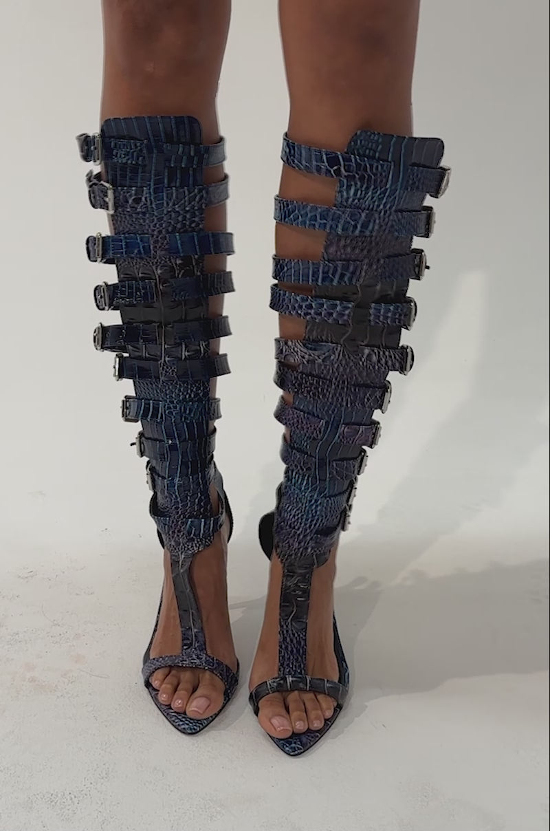 Video of a woman modeling the AZALEA WANG CHERLLI MULTI GLADIATOR CROC SANDAL, featuring strappy stiletto heels in a shiny blue snakeskin pattern.