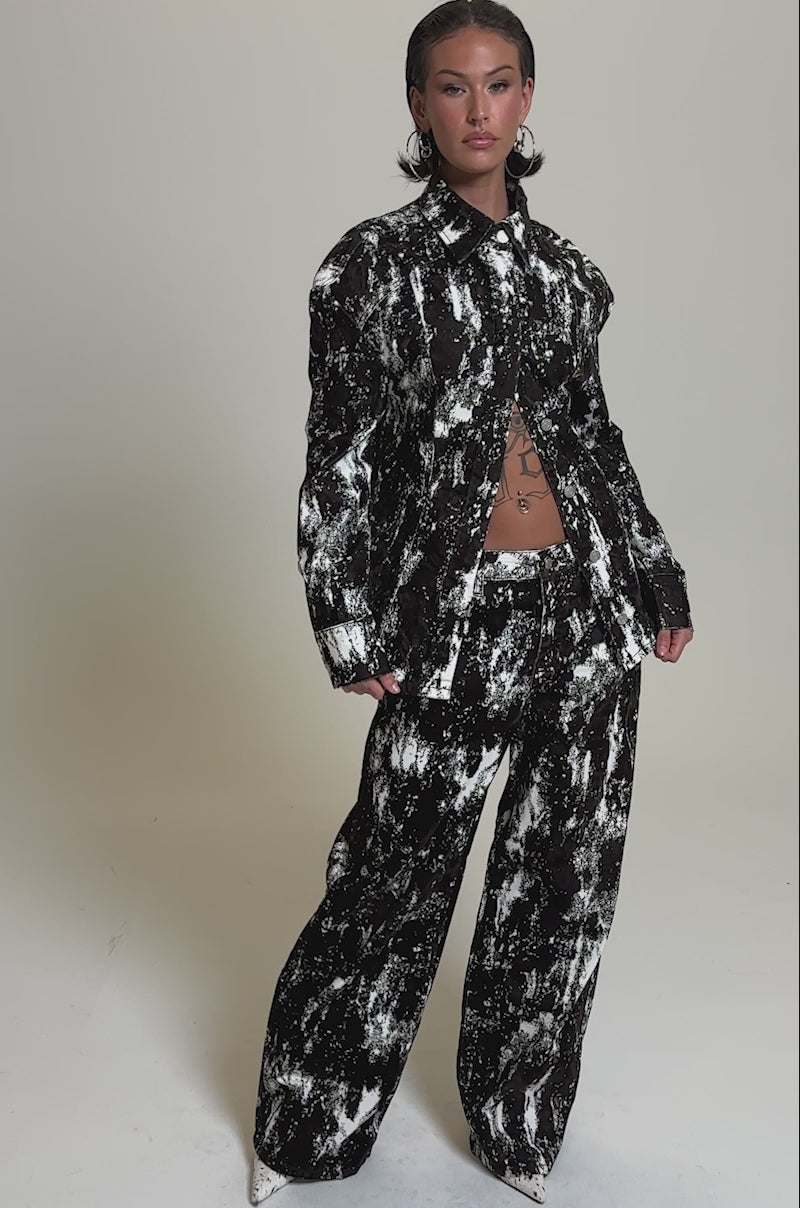 A video of a person in the CRAZY IN LOVE TROUSER suit, featuring a brown and white tie-dye pattern, wide-leg silhouette, and buttoned-up jacket. 