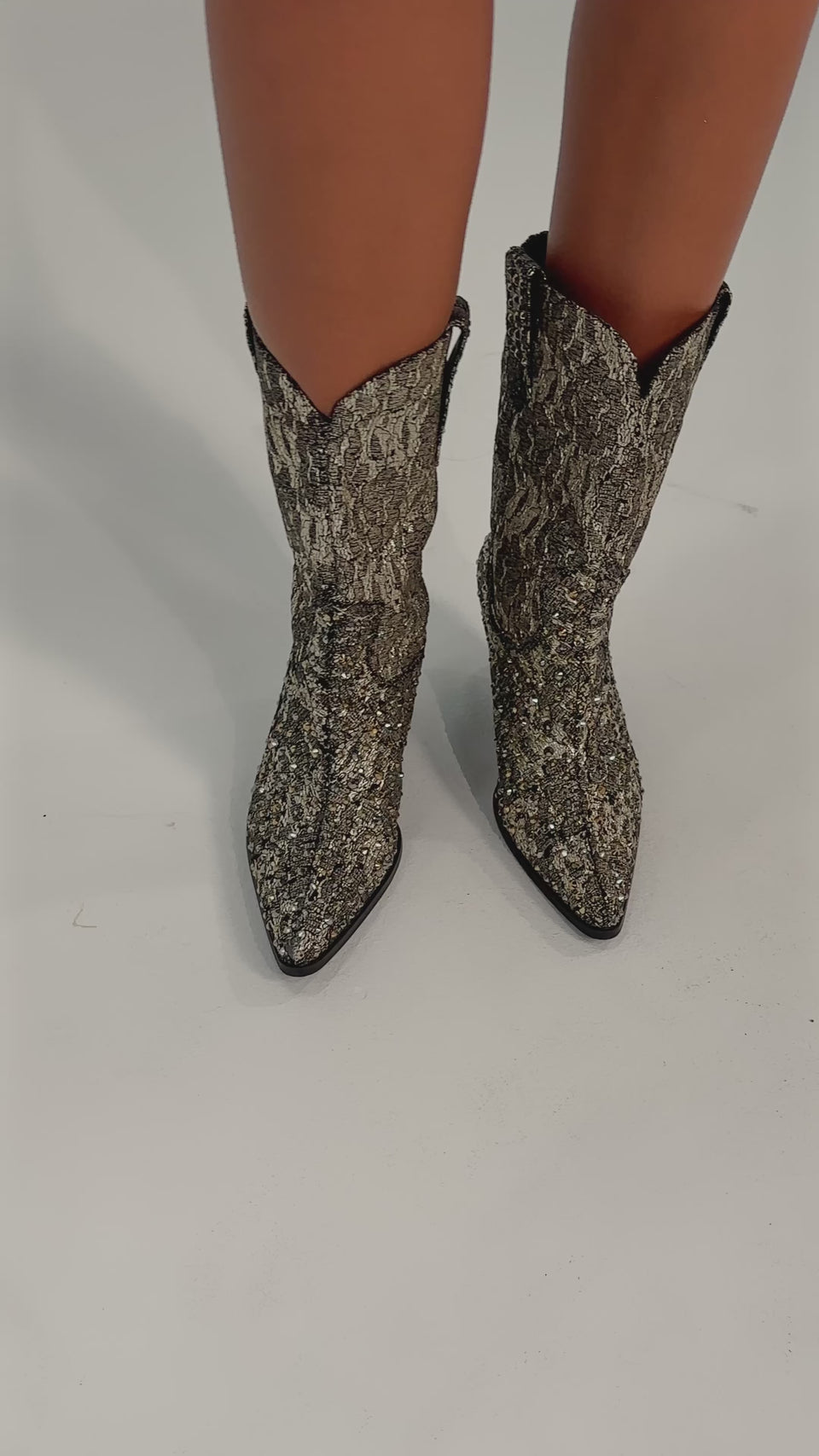 A video of a person wearing only the AZALEA WANG ZIRENNE Gold and Black Brocade Rhinestone Embellished Western Boots—mid-calf height with a pointed toe. 
