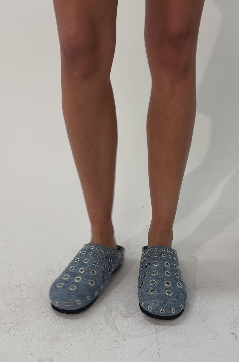 A video of a person wearing the AZALEA WANG MARSHA DENIM GROMMET DETAIL FLAT with striking silver grommet accents.