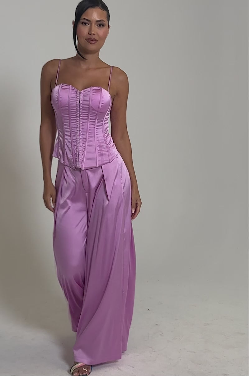 Video of woman modeling the IN FULL BLOOM LIGHT PURPLE TROUSER, featuring shiny satin fabric, wide-leg tailored pants, and a fitted corset top. 