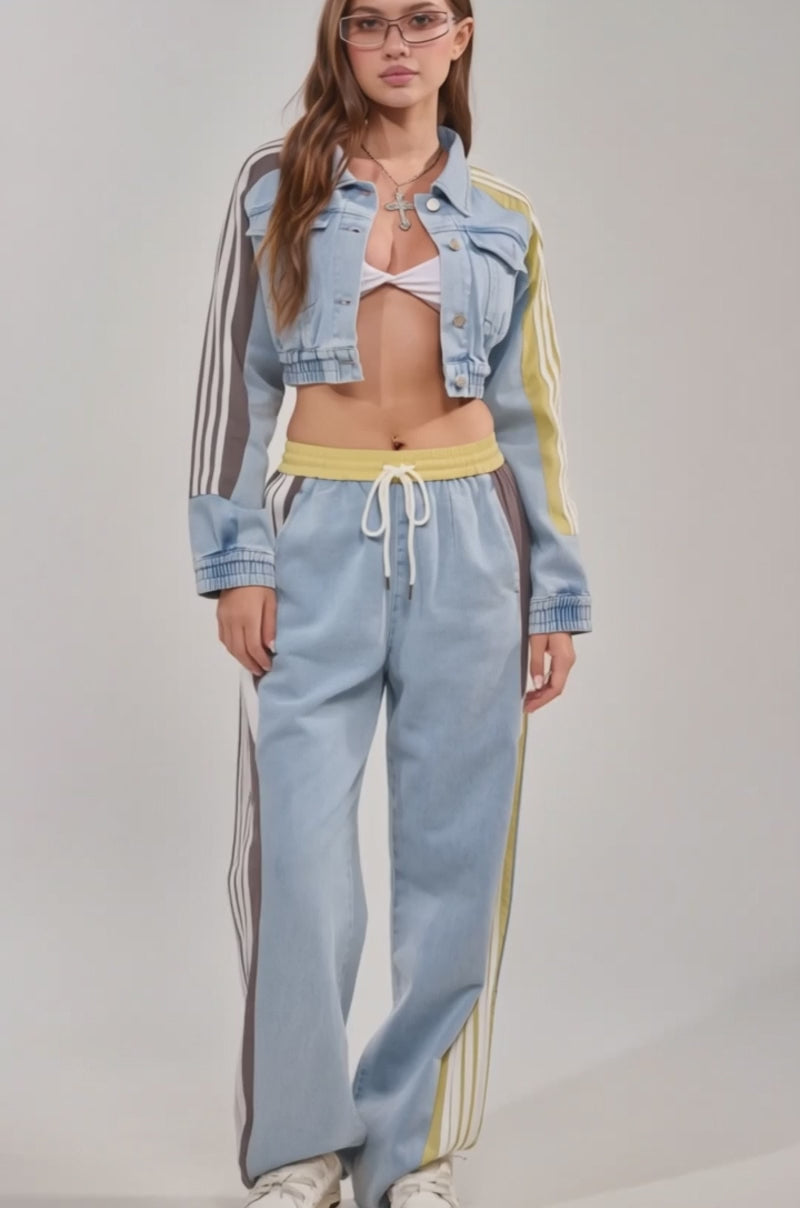Video of woman modeling the NEVER BETTER DENIM JACKET, a cropped design with yellow and white stripes, styled with a white bralette, loose denim pants featuring yellow trim, glasses, and layered necklaces for a retro athleisure vibe.