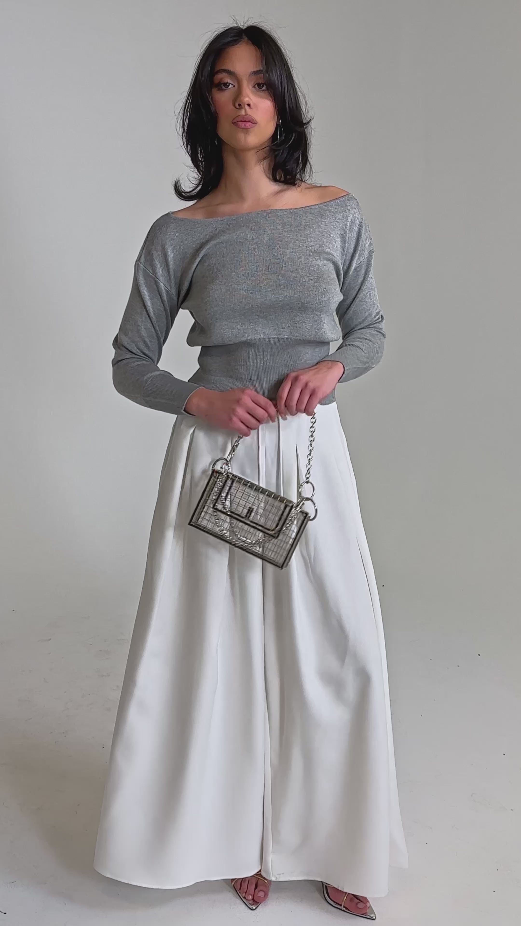 A video of a woman in a gray off-the-shoulder sweater and the GLORIOUS PLEATED WIDE LEG TROUSER—essential white wide-leg pants. 