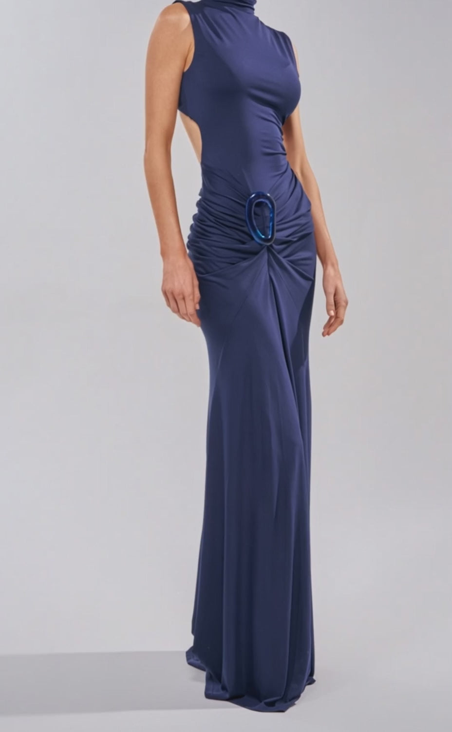 A video of a woman wearing the BE MY DATE BODYCON MAXI DRESS IN NAVY—sleeveless, floor-length, with a high neckline, gathered waist detail, and accented by a large circular buckle.