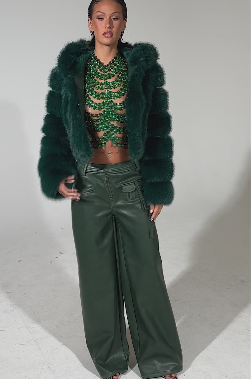A video of a woman wearing the JOLENE FAUX FUR COAT IN EMERALD GREEN and a green necklace from AKIRA.