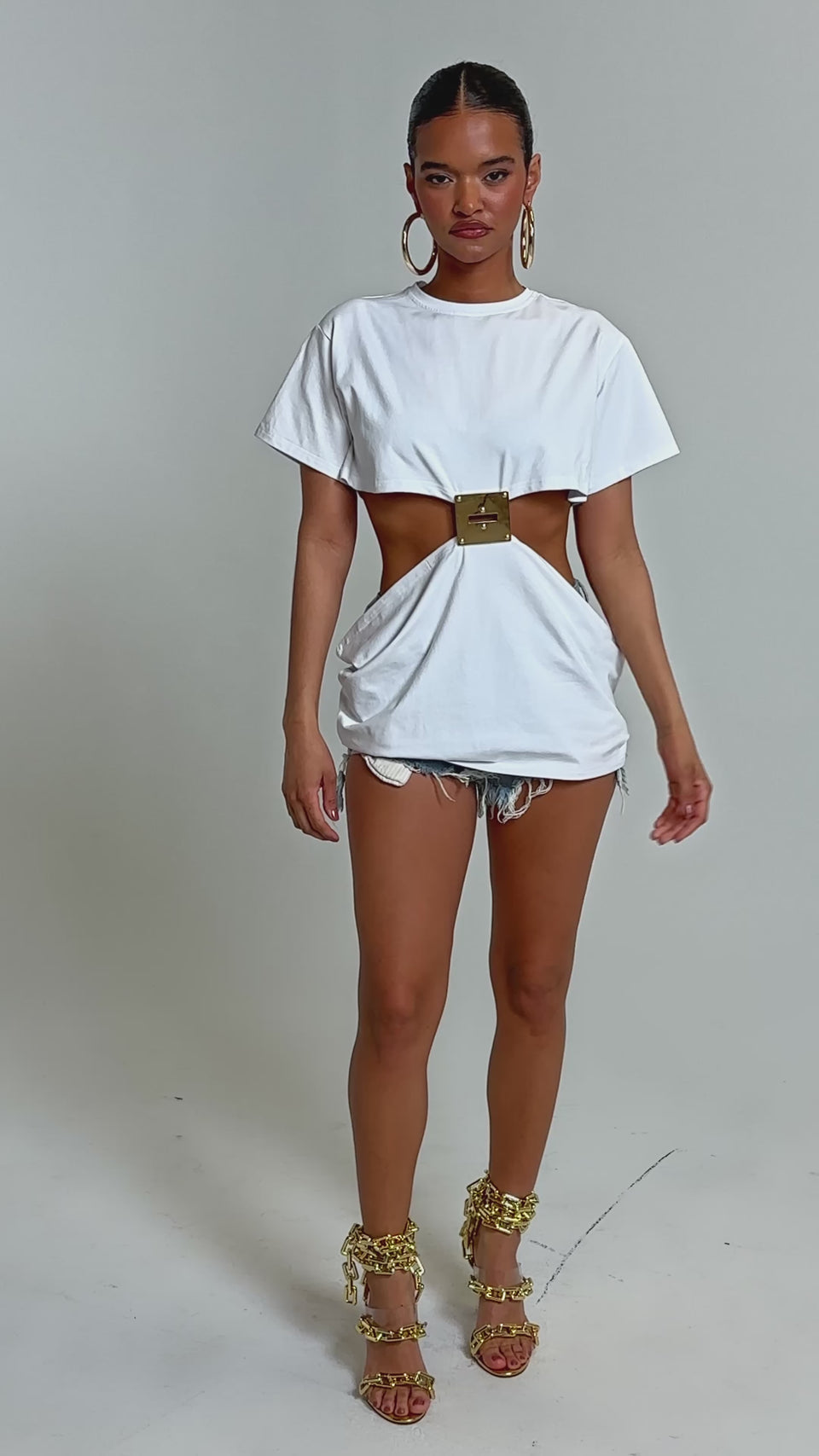 Video of woman modeling the GIRL BOSS MOMENTS CUT OUT TSHIRT styled with large hoop earrings and distressed denim shorts.