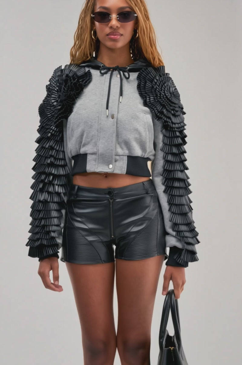 Video of a woman modeling the MADE YOU LOOK BOMBER WITH PU TRIM, featuring textured, layered black sleeves and a gray cropped design.