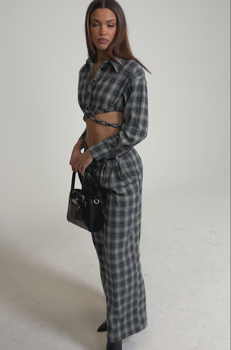 Video of woman modeling the JANE PLAID BUTTON DOWN, a cropped plaid top with a front twist detail, paired with matching high-waisted pants
