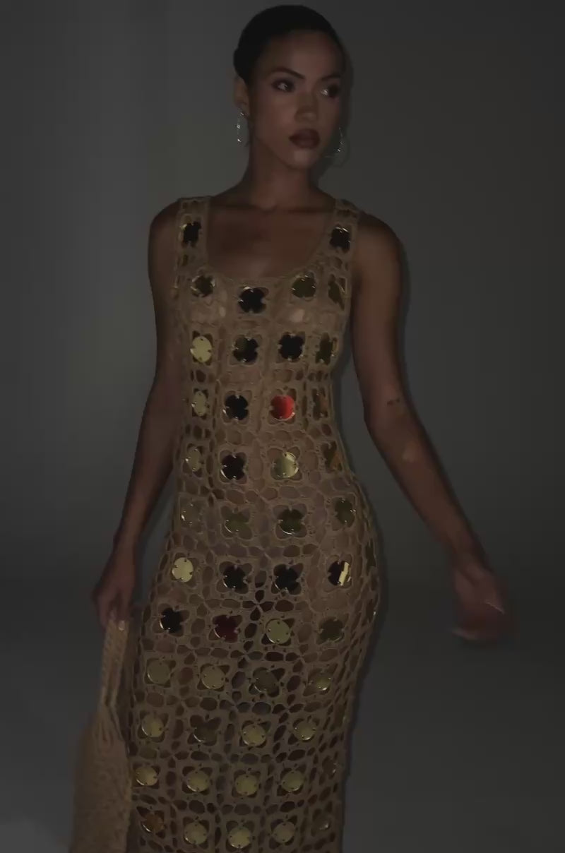 Video of woman modeling the HOT GIRL AGENDA SEQUIN CROCHET MIDI DRESS—sleeveless, beige, with floral patterns and gold disc embellishments—styled with gold platform heels, hoop earrings, and a matching crochet bag.