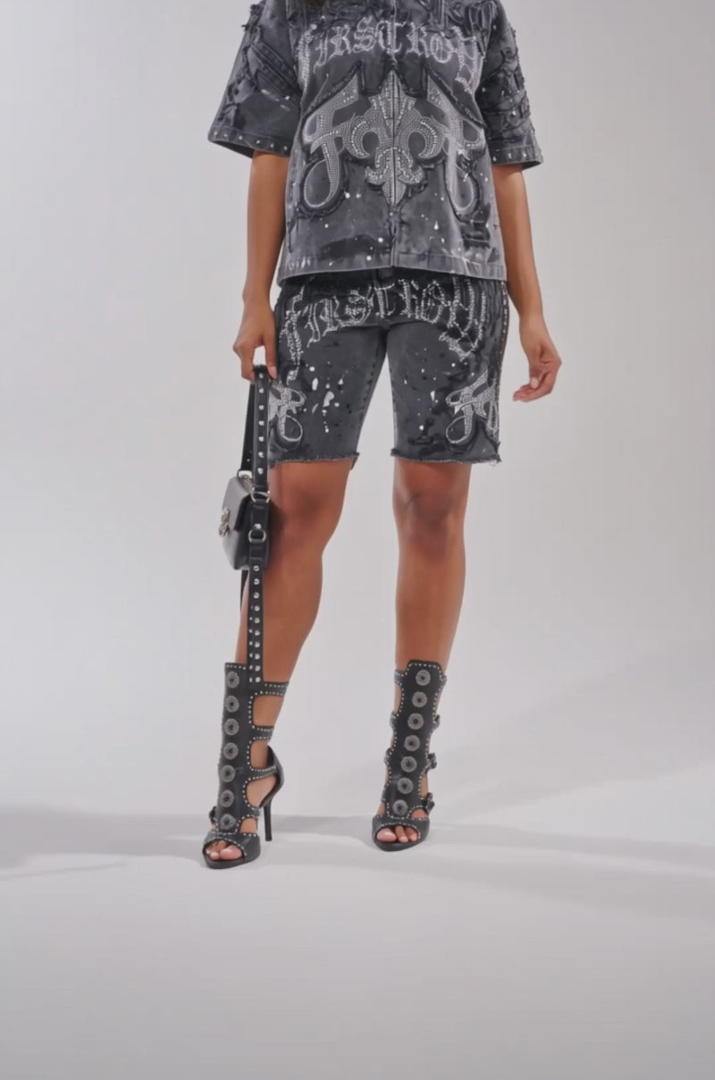 A video of a woman wearing the NOT LIKE THE REST EMBELLISHED TOP with black studded boots, sunglasses, matching shorts, and carrying a black handbag.