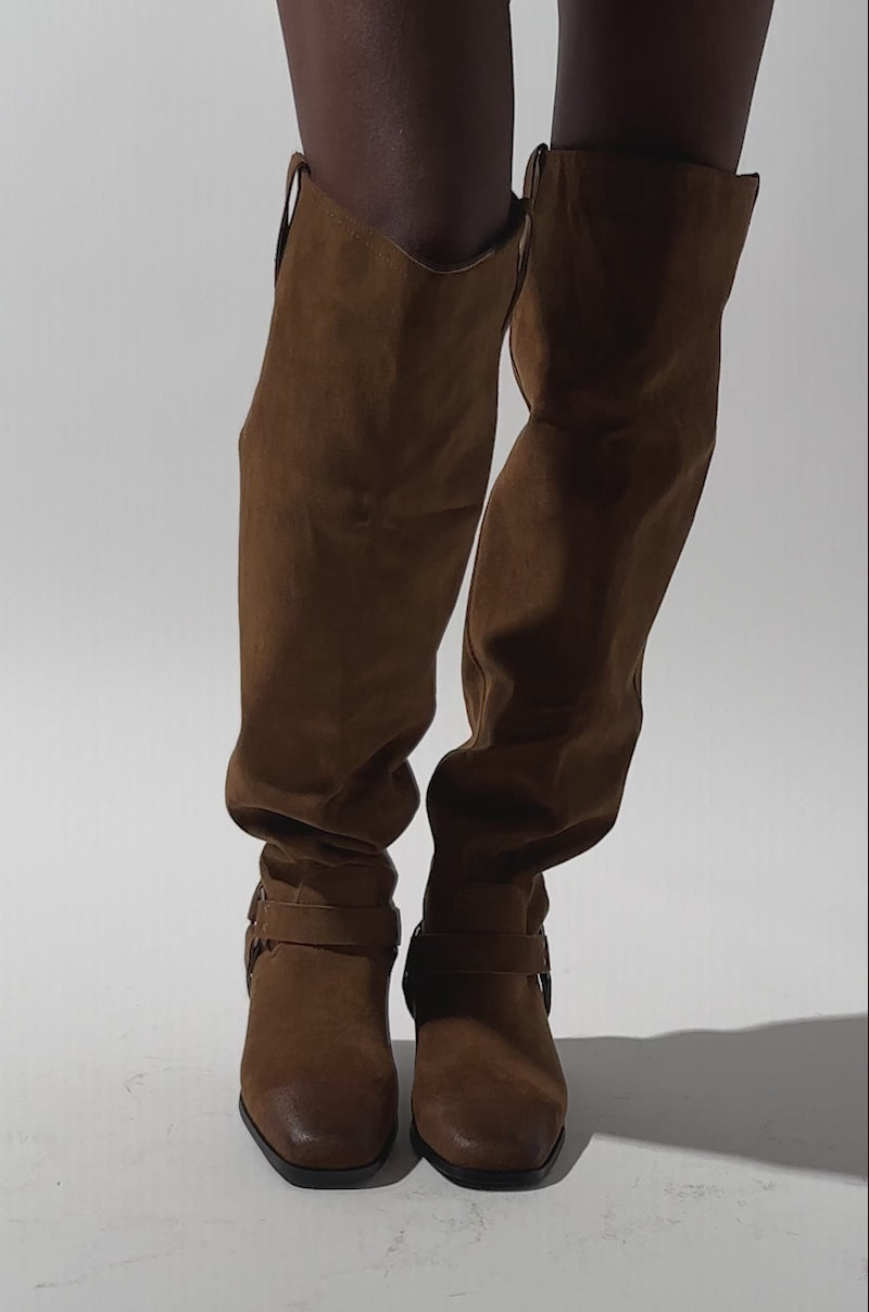A video of a person standing against a plain background wearing distressed denim shorts and the AZALEA WANG FLAT OVER THE KNEE RIDING BOOT.