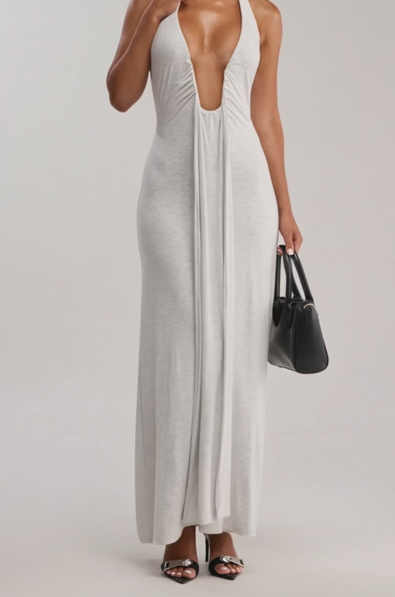 Video of woman modeling the MAKE YOU LOSE YOUR MIND MAXI DRESS IN LIGHT GREY with black high-heeled sandals, hoop earrings and a black handbag