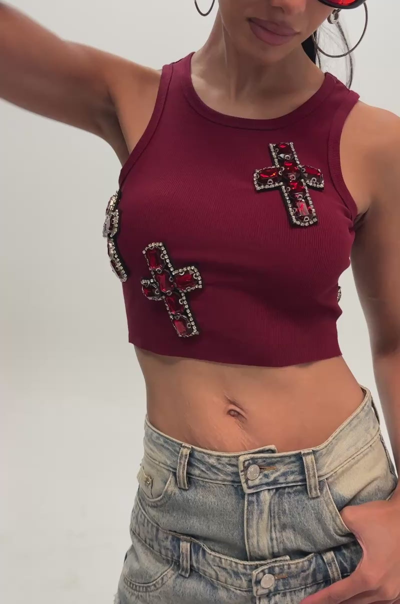 Video of a woman modeling the BLESSED TANK IN BURGUNDY—a sleeveless embellished crop top with jeweled cross designs.