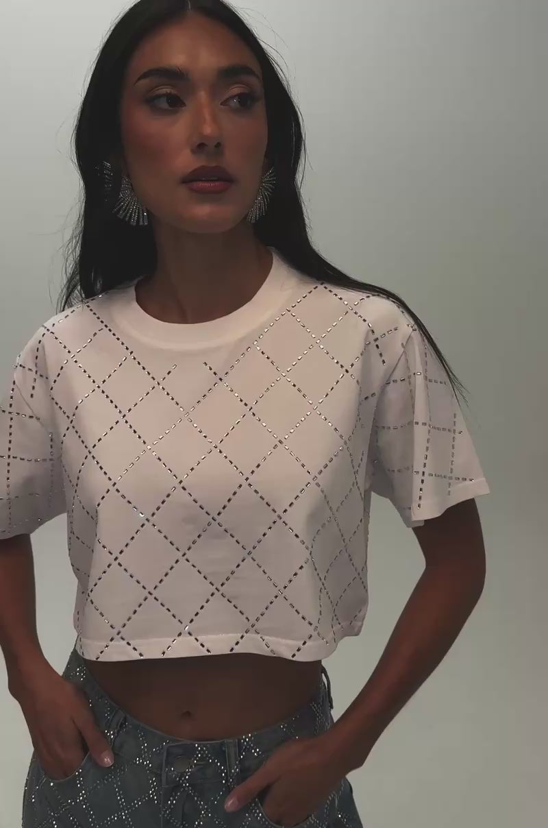 Video of a woman modeling the DIAMOND DUST RHINESTONE TEE—a white cropped top featuring a sparkling rhinestone diamond cutout pattern.