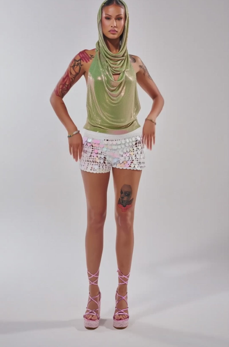 Video of woman modeling the IN MY MIND HOODED CHAINMAIL TOP IN GREEN and a white sequin skirt, standing against a plain background.