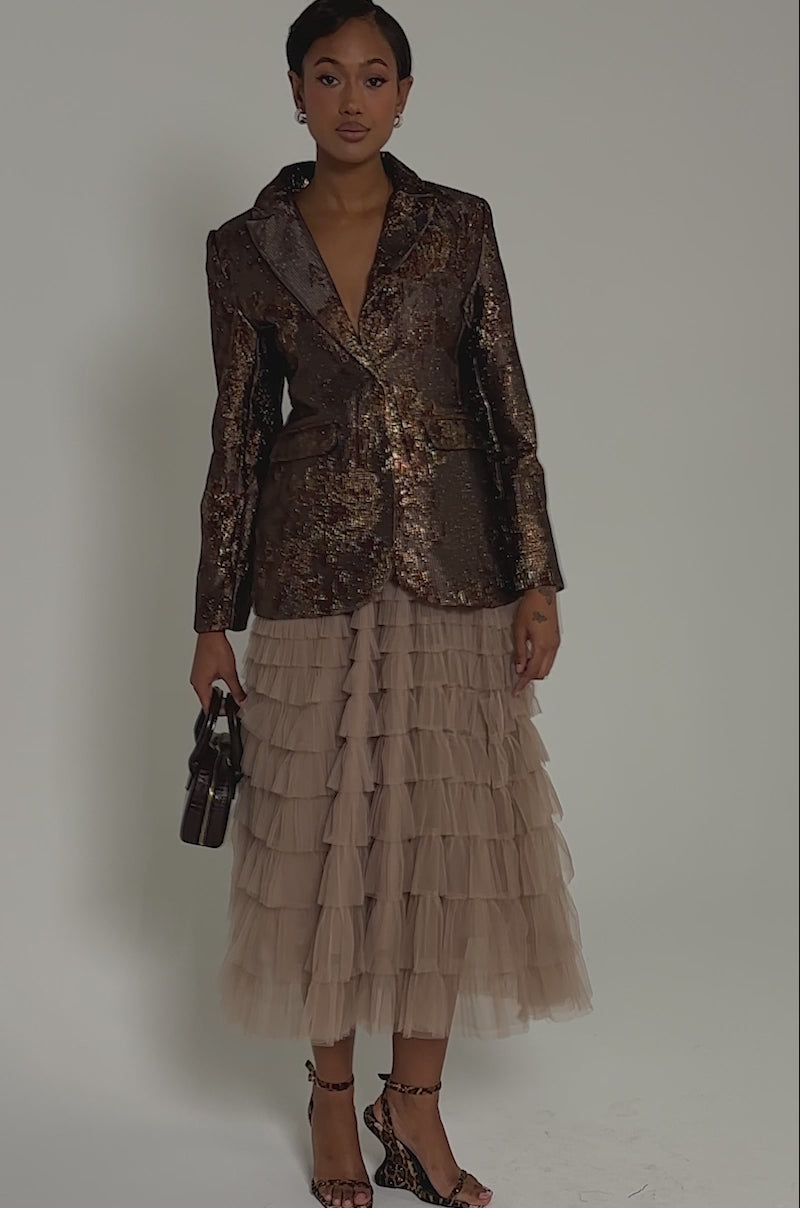 Video of woman modeling the CELESTE EMBELLISHED BROCADE BLAZER over a ruffled beige skirt, standing against a plain gray background and looking confidently at the camera.