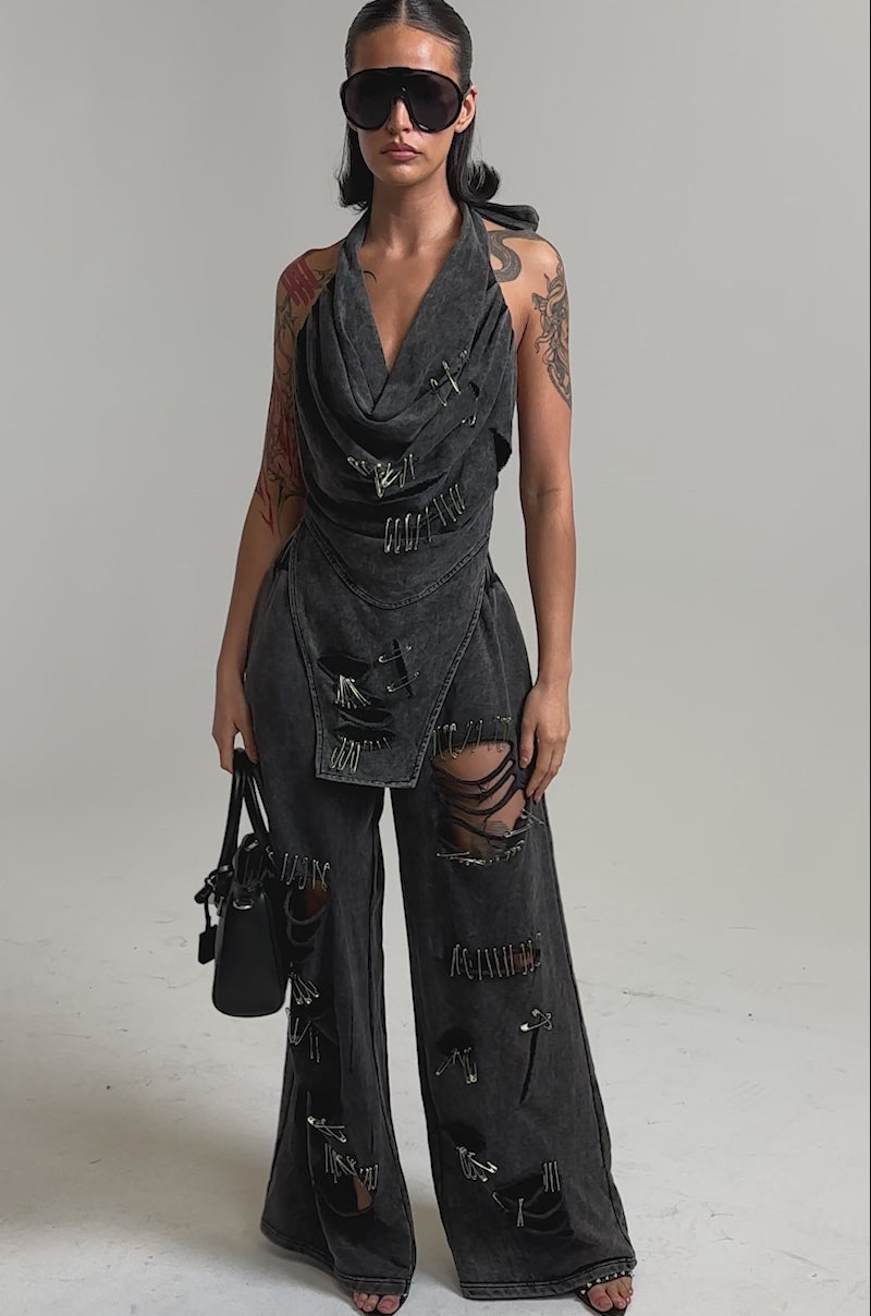 A video of a woman in the LEILA DISTRESSED COWL NECK TOP with safety-pin accents. She pairs it with sunglasses and a black handbag.