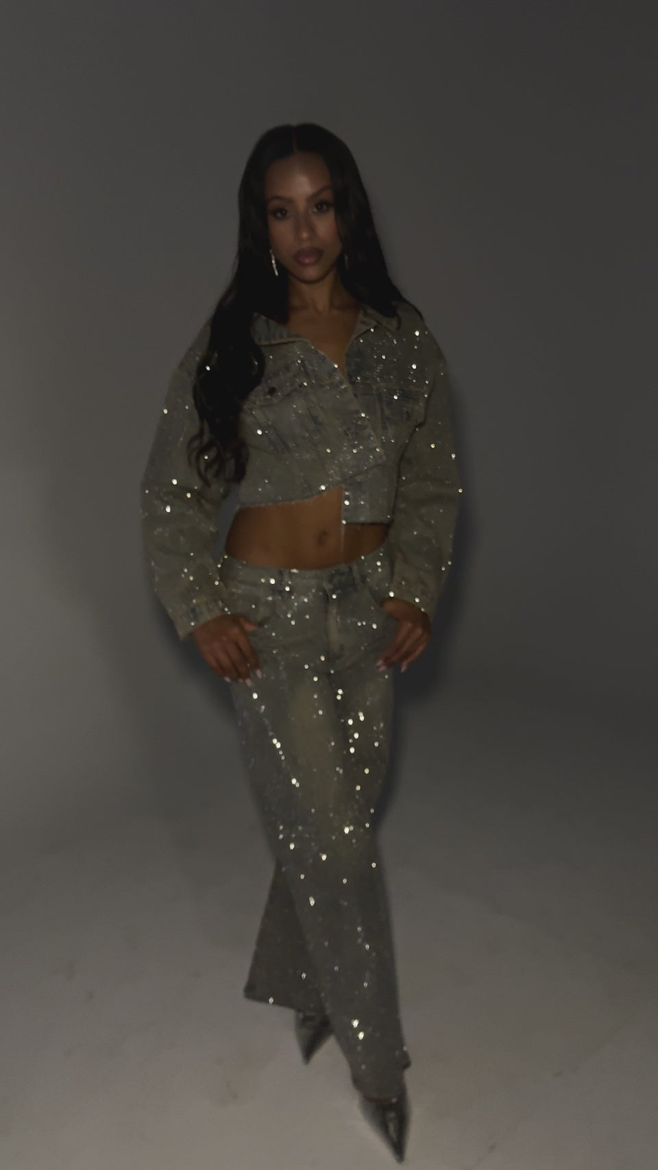 Video of woman modeling the DEMI EMBELLISHED DENIM JACKET, styled off one shoulder to show her midriff, paired with matching jeans.