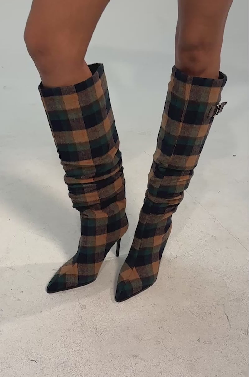 Video of woman modeling the AZALEA WANG WISHBONE PLAID PRINT STILETTO BOOT—knee-high, pointed toe boots with a plaid knit design in green, brown, and tan against a light background.