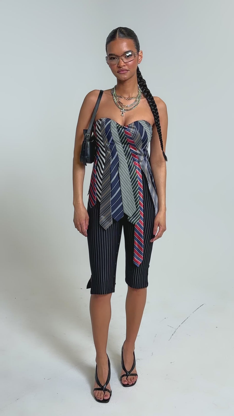 Video of woman modeling the BUSINESS ONLY CAPRI—black high-rise slim-leg pinstripe trousers—with open-toe heeled shoes, standing against a plain light background.