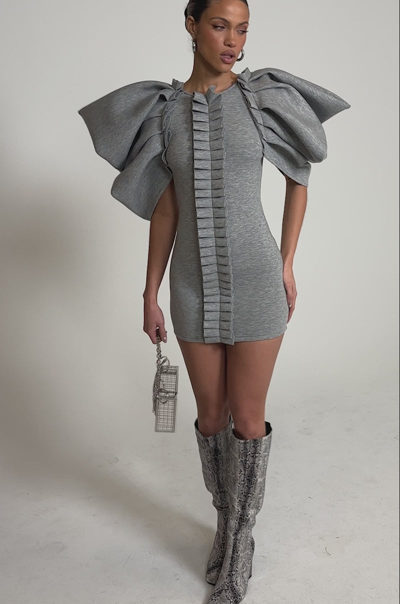 A video of a woman in the SPREAD MY WINGS MINI DRESS in heather grey, featuring ruffle sleeves and a central ruffle. 