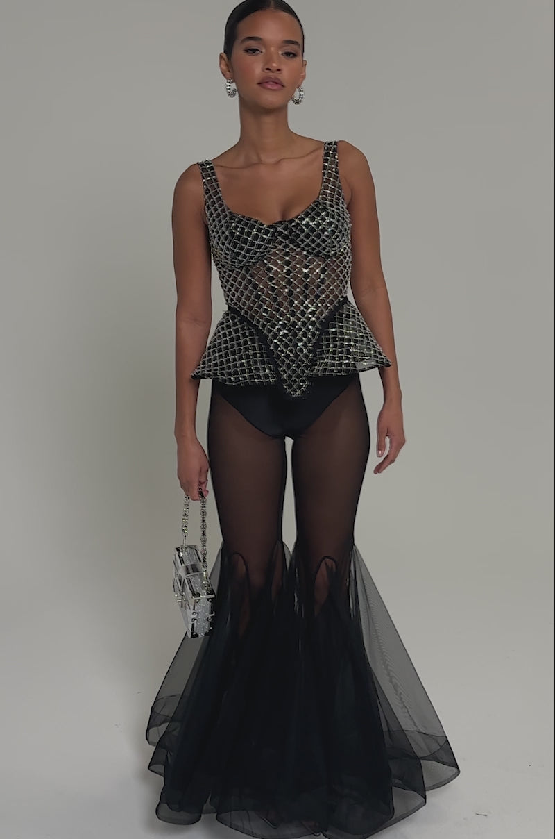 Video of woman modeling the GLITZ AND GLAM SHEER RHINESTONE CORSET with white grid details, styled over a fringed black skirt and finished with a beaded statement choker.